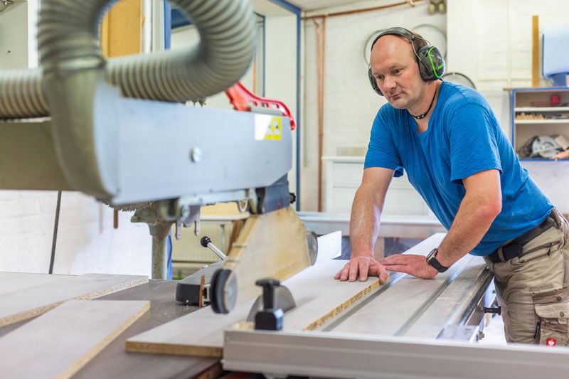 Arbeiter schneidet Holz mit Kreissaege